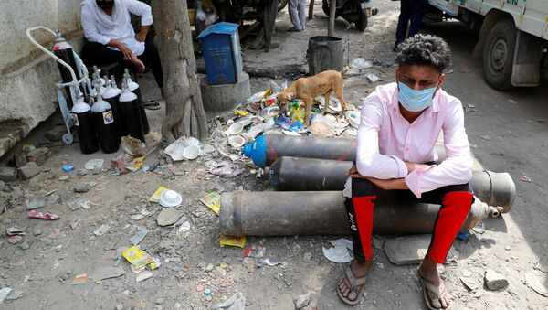 Sumit Kumar, 28, sits on an oxygen cylinder as he waits outside a factory to get it refilled, as the number of infections from the coronavirus disease (COVID-19) soars in New Delhi, India. - Sputnik International