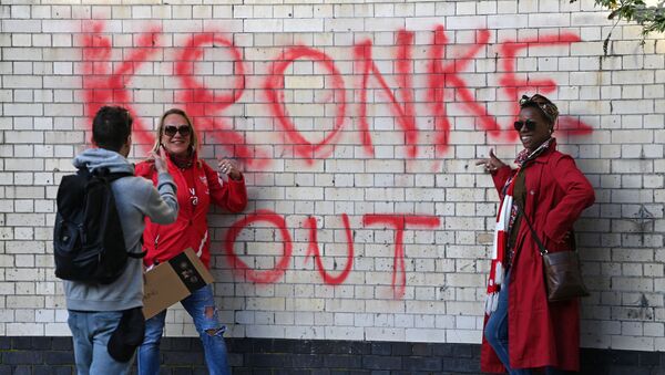 Two fans have their photograph taken beside a Kronke Out message sprayed on a wall as supporters protest against Arsenal's US owner Stan Kroenke, outside English Premier League club Arsenal's Emirates stadium in London on 23 April 2021, ahead of their game against Everton. - Sputnik International