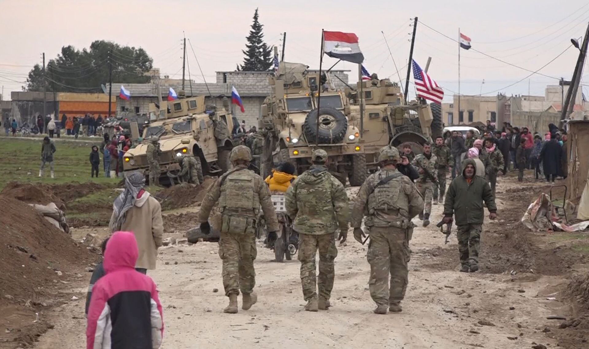 In this frame grab from video, Russian, Syrian and others gather next to an American military convoy stuck in the village of Khirbet Ammu, east of Qamishli city, Syria, Wednesday, Feb. 12, 2020. The Syrian official news agency SANA, said Wednesday, that locals had gathered at an army checkpoint, pelting the U.S. convoy with stones and taking down a U.S. flag flying on a vehicle when troops fired with live ammunition and smoke bombs. (AP Photo) - Sputnik International, 1920, 07.09.2021
