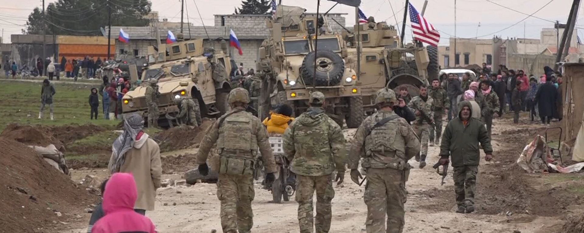 In this frame grab from a video, Russians, Syrians and others gather next to an American military convoy stuck in the village of Khirbet Ammu, east of Qamishli city, Syria, 12, February 2020. Syria's official news agency SANA said that locals had gathered at an army checkpoint, pelting the U.S. convoy with stones and taking down a US flag flying on a vehicle when troops fired with live ammunition and smoke bombs. (AP Photo) - Sputnik International, 1920, 06.05.2021