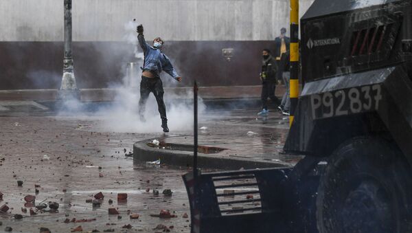 A demonstrator throws a stone at riot police vehicle during a protest against President Ivan Duque's government at the Bolivar square in Bogota on May 5, 2021. - Thousands of people returned to the streets of Colombia on Wednesday in rejection of the government of Ivan Duque, who has completed a week of pressure with demonstrations that turned violent in some cities and left some twenty people dead.  - Sputnik International