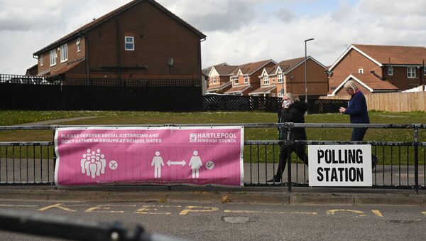 People walk past banners for a polling station in Hartlepool, County Durham on 6 May 2021, as voters cast their ballots in local elections. - Sputnik International