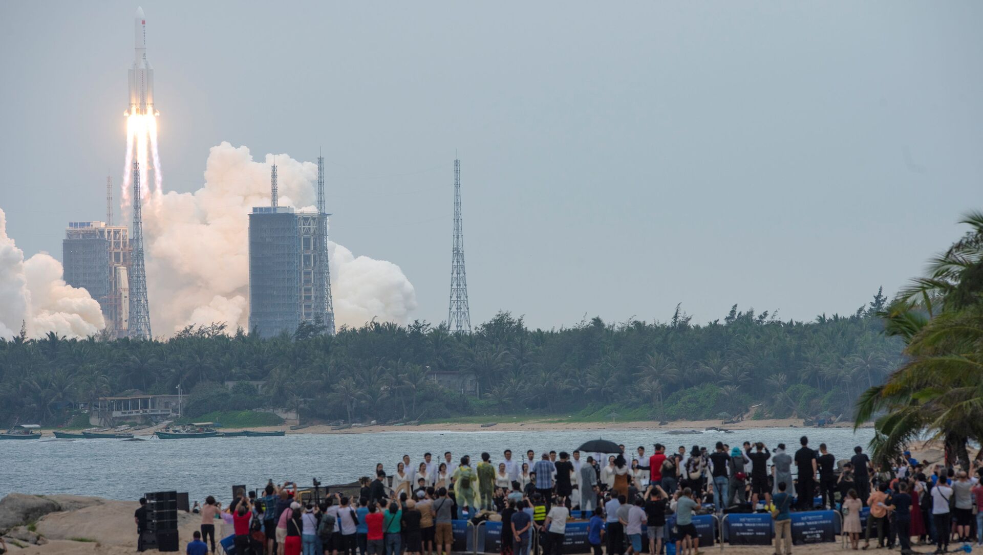People watch from a beach as the Long March-5B Y2 rocket, carrying the core module of China's space station Tianhe, takes off from Wenchang Space Launch Center in Hainan province, China April 29, 2021. - Sputnik International, 1920, 07.05.2021