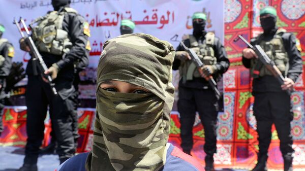 A masked Palestinian boy looks on as Hamas militant take part in a protest over the possible eviction of several Palestinian families from homes on land claimed by Jewish settlers in the Jerusalem's Sheikh Jarrah neighbourhood, in the northern Gaza Strip on May 7, 2021. - Sputnik International