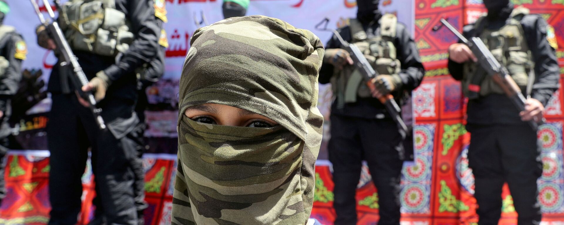 A masked Palestinian boy looks on as Hamas militant take part in a protest over the possible eviction of several Palestinian families from homes on land claimed by Jewish settlers in the Jerusalem's Sheikh Jarrah neighbourhood, in the northern Gaza Strip on May 7, 2021. - Sputnik International, 1920, 16.05.2021