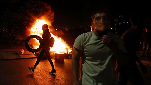 A Palestinian woman demonstrator carries a tire as she walks past a burning barricade during an anti-Israel protest over tension in Jerusalem, near the Jewish settlement of Beit El near Ramallah, in the Israeli-occupied West Bank May 9, 2021 - Sputnik International