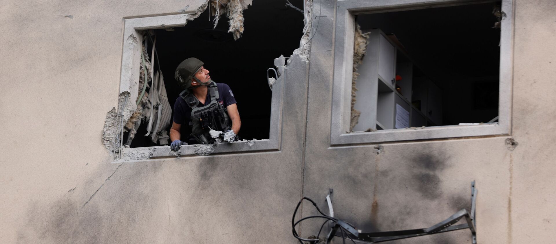 Эксперт по обезвреживанию бомб израильской полиции смотрит из окна жилого дома, который был поврежден после попадания в него ракеты, запущенной из сектора Газа, в Ашкелоне - Sputnik International, 1920