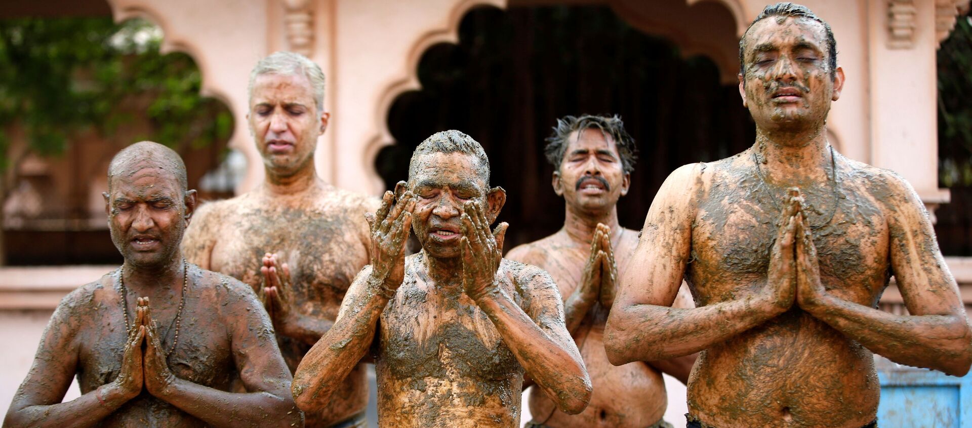 People pray after applying cow dung on their bodies during cow dung therapy, believing it will boost their immunity to defend against the coronavirus disease (COVID-19) at the Shree Swaminarayan Gurukul Vishwavidya Pratishthanam Gaushala or cow shelter on the outskirts of Ahmedabad, India, May 9, 2021 - Sputnik International, 1920