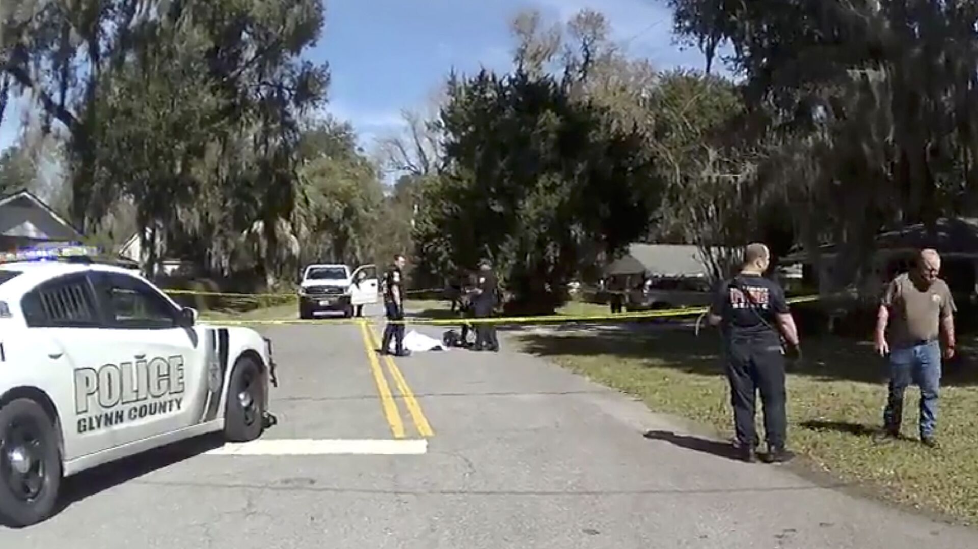 In this Feb. 23, 2020 image taken from Glynn, Ga., County Police body camera video, authorities, rear, stand over the covered body of Ahmaud Arbery, a 25-year-old Black man, who was shot and killed while while running in a neighborhood outside the port city of Brunswick, Ga. - Sputnik International, 1920, 23.11.2021