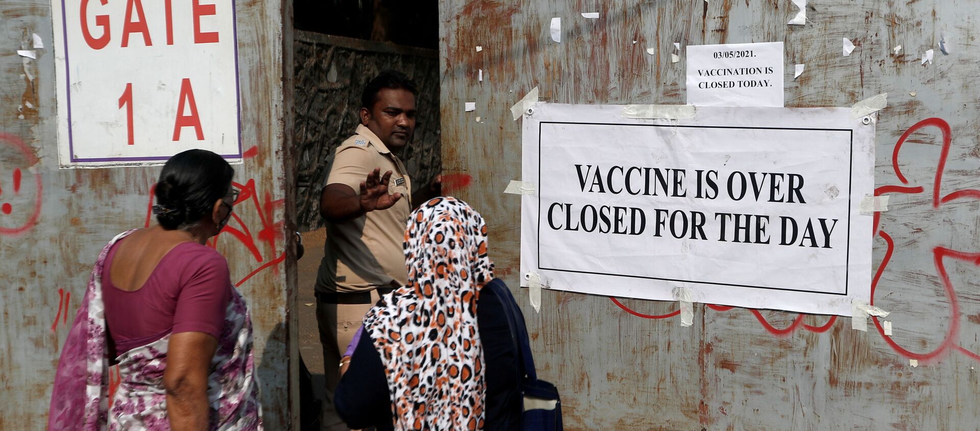 A policeman asks people who came to receive a dose of a coronavirus disease (COVID-19) vaccine to leave as they stand outside the gate of a vaccination centre which was closed due to unavailability of the supply of COVID-19 vaccine, in Mumbai, India, May 3, 2021.  - Sputnik International, 1920