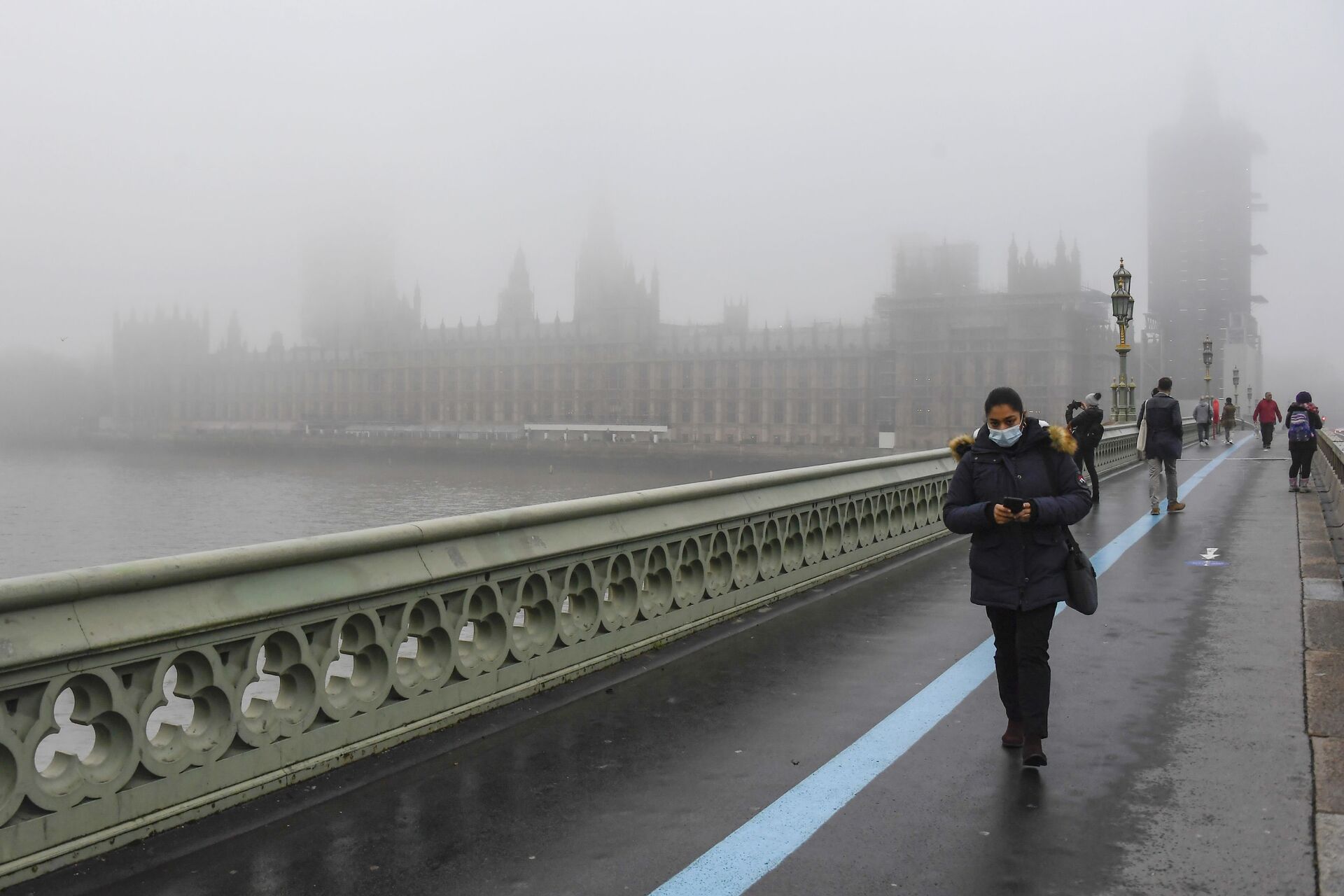People wearing face masks, walk over Westminster Bridge with the Houses of Parliament shrouded by fog, in London, Tuesday, Dec. 8, 2020 - Sputnik International, 1920, 27.12.2021