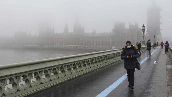 People wearing face masks, walk over Westminster Bridge with the Houses of Parliament shrouded by fog, in London, Tuesday, Dec. 8, 2020 - Sputnik International