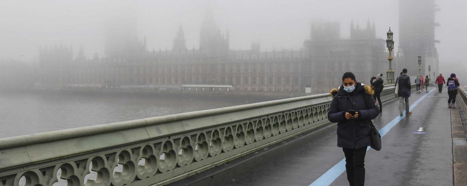 People wearing face masks, walk over Westminster Bridge with the Houses of Parliament shrouded by fog, in London, Tuesday, Dec. 8, 2020 - Sputnik International, 1920, 21.10.2021
