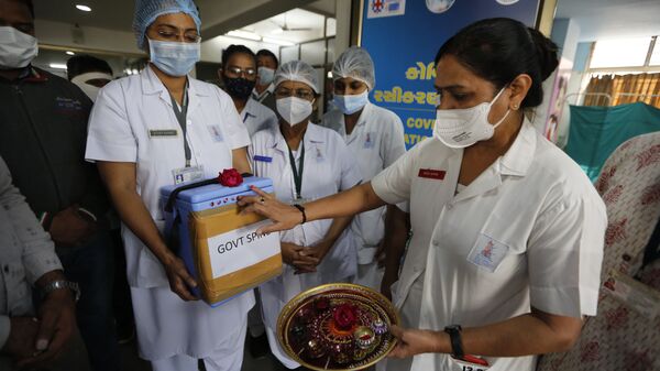 A nurse, right, performs rituals to a box containing COVID-19 vaccines upon its arrival at a government Hospital in Ahmedabad, India, Saturday, Jan. 16, 2021 - Sputnik International