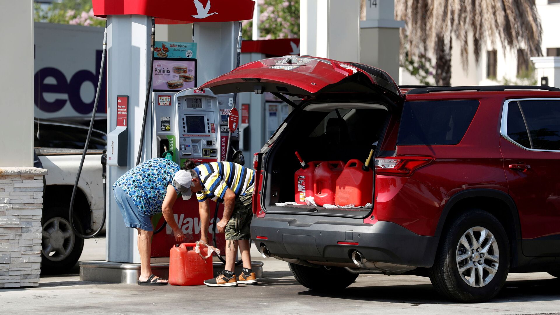 A couple fills up multiple 5 gallon gas tanks at a Wawa gas station, after a cyberattack crippled the biggest fuel pipeline in the country, run by Colonial Pipeline, in Tampa, Florida, U.S., May 12, 2021. - Sputnik International, 1920, 08.03.2022