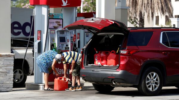 A couple fills up multiple 5 gallon gas tanks at a Wawa gas station, after a cyberattack crippled the biggest fuel pipeline in the country, run by Colonial Pipeline, in Tampa, Florida, U.S., May 12, 2021. - Sputnik International