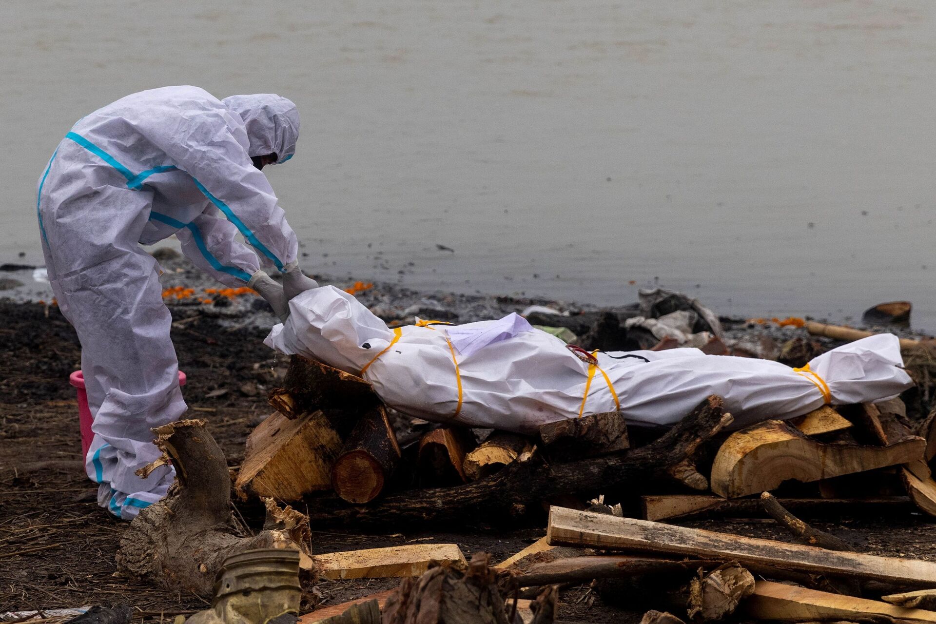 A man wearing a protective suit touches the body of his relative, who died from the coronavirus disease (COVID-19), before his cremation on the banks of the river Ganges at Garhmukteshwar in the northern state of Uttar Pradesh, India, May 6, 2021. - Sputnik International, 1920, 07.09.2021