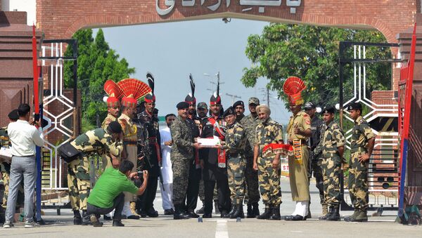 Indian Border Security Force (BSF) commandant Sudeep (centre R) presents sweets to Pakistani Wing Commander Bilal (centre L) on the occasion of the Eid al-Adha festival at the India-Pakistan Wagah border post on September 2, 2017 - Sputnik International