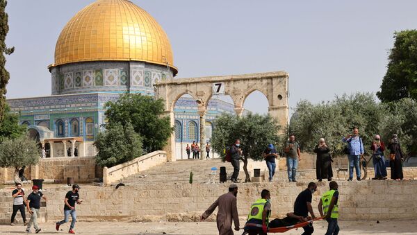 Palestinian medics walk near the Dome of the Rock as they evacuate on a stretcher a wounded protester from the Aqsa mosque compound in Jerusalem's Old City on May 10, 2021, amidst clashes with Israeli security forces.  - Sputnik International