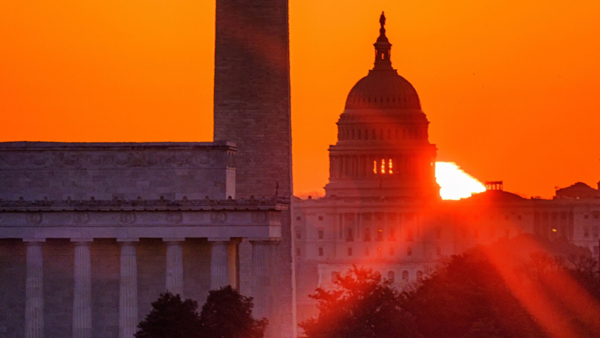 The sun flares through the camera lens as it rises behind the U.S. Capitol building, Washington Monument and the Lincoln Memorial, Monday, March 22, 2021, in Washington. - Sputnik International, 1920, 11.05.2022