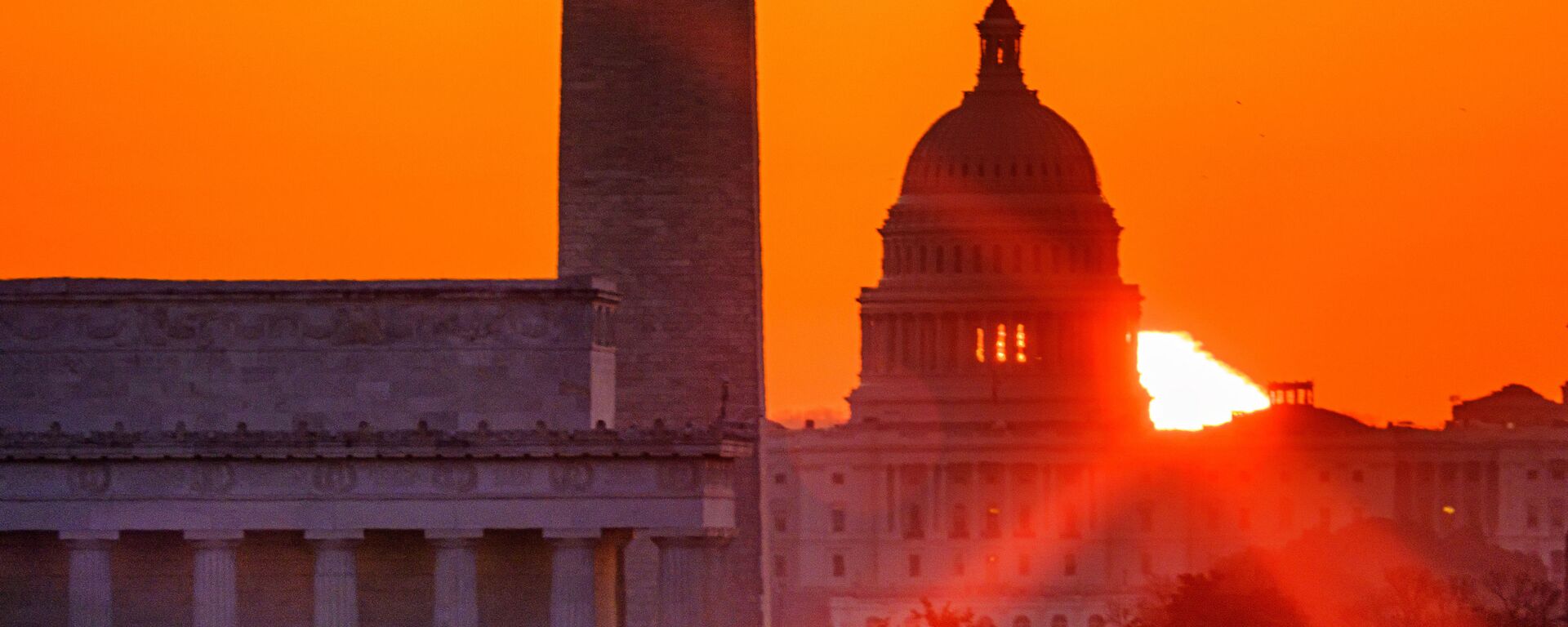 The sun flares through the camera lens as it rises behind the U.S. Capitol building, Washington Monument and the Lincoln Memorial, Monday, March 22, 2021, in Washington. - Sputnik International, 1920, 11.05.2022