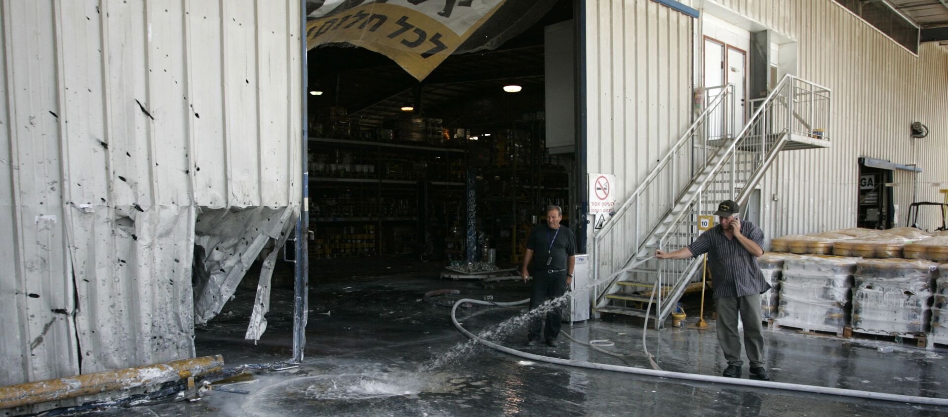 An Israeli worker uses a hose to clean at the scene  where a mortar fired by Palestinian militants in Gaza hit a factory in the southern Israeli kibbutz of Nir Oz,Thursday, June 5, 2008 - Sputnik International, 1920