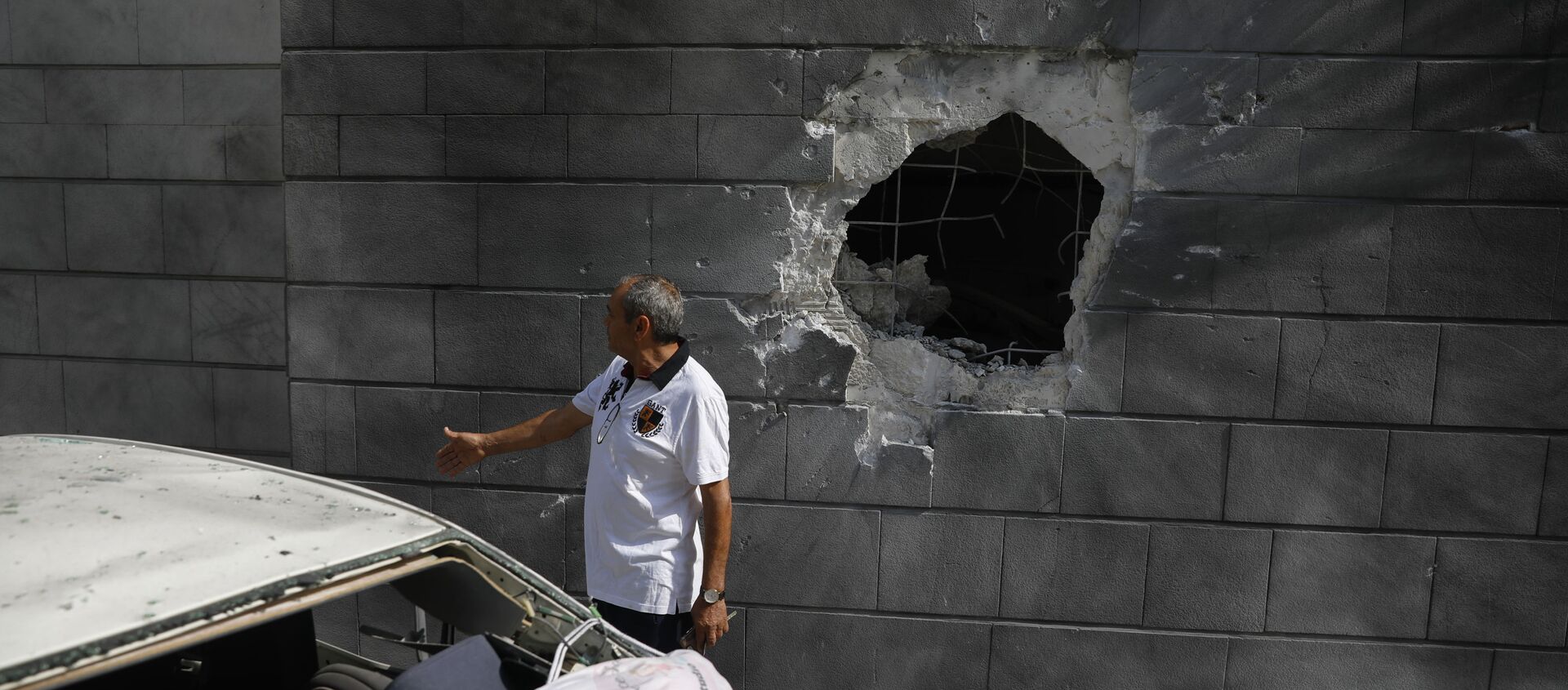 A man inspects the damaged wall of a residential building that was hit by a rocket fired from the Gaza Strip in Ashkelon, Israel, Friday, May 14, 2021.  - Sputnik International, 1920