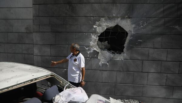 A man inspects the damaged wall of a residential building that was hit by a rocket fired from the Gaza Strip in Ashkelon, Israel, Friday, May 14, 2021.  - Sputnik International