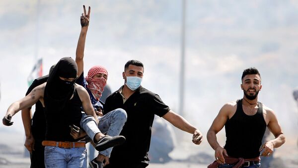 An injured Palestinian demonstrator gestures as he is evacuated during clashes with Israeli forces at a protest over tension in Jerusalem and Israel-Gaza escalation, near Hawara checkpoint near Nablus in the Israeli-occupied West Bank, May 14, 2021. - Sputnik International