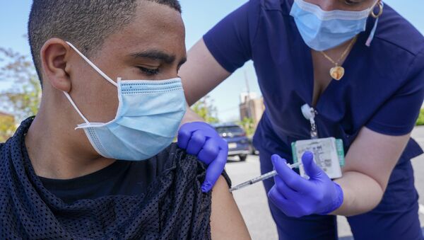 Justin Bishop, 13, watches as Registered Nurse Jennifer Reyes inoculates him with the first dose of the Pfizer COVID-19 vaccine at the Mount Sinai South Nassau Vaxmobile parked at the De La Salle School, Friday, 14 May 2021, in Freeport, NY. - Sputnik International