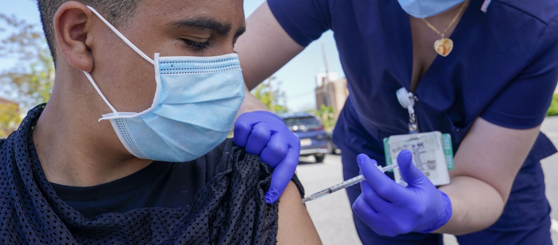 Justin Bishop, 13, watches as Registered Nurse Jennifer Reyes inoculates him with the first dose of the Pfizer COVID-19 vaccine at the Mount Sinai South Nassau Vaxmobile parked at the De La Salle School, Friday, May 14, 2021, in Freeport, N.Y.  - Sputnik International, 1920