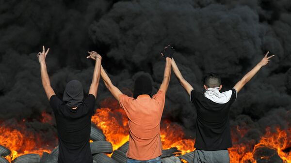 Palestinian demonstrators look at burning tyres during a protest over tensions in Jerusalem and Israel-Gaza escalation, in the Israeli-occupied West Bank, 16 May 2021. - Sputnik International