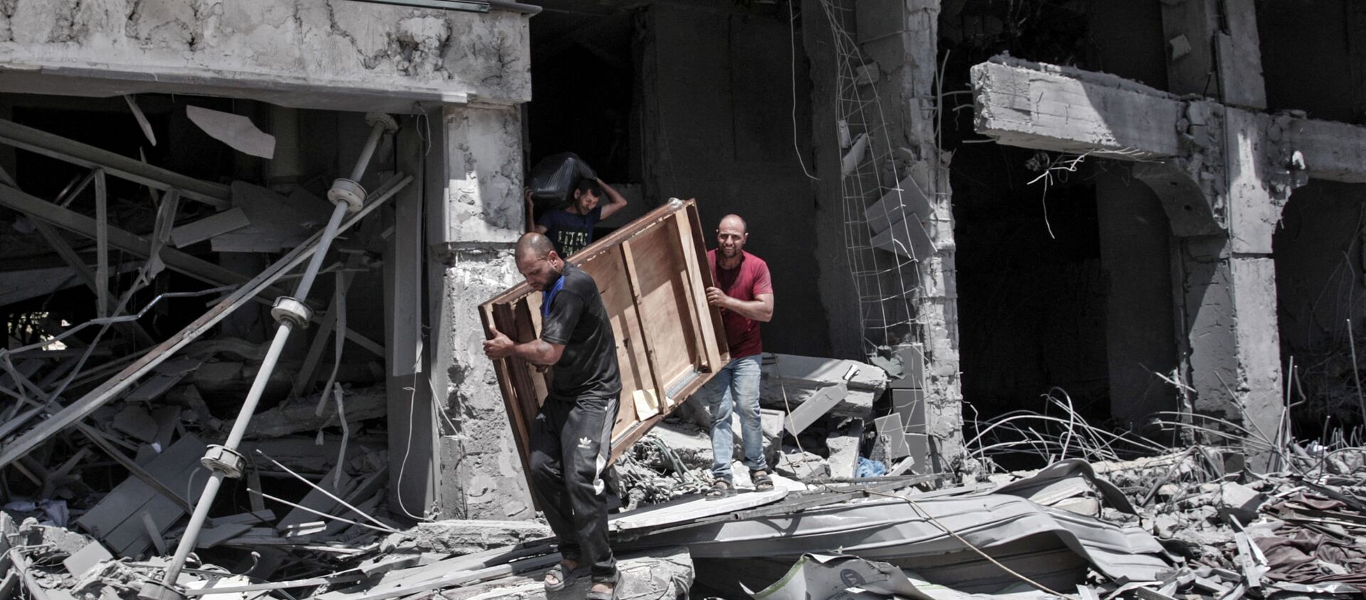 Palestinian men remove salvageable items from the bombarded Al-Jawhara Tower in Gaza City on May 17, 2021, five days after it was targeted by Israeli airstrikes. - Sputnik International, 1920
