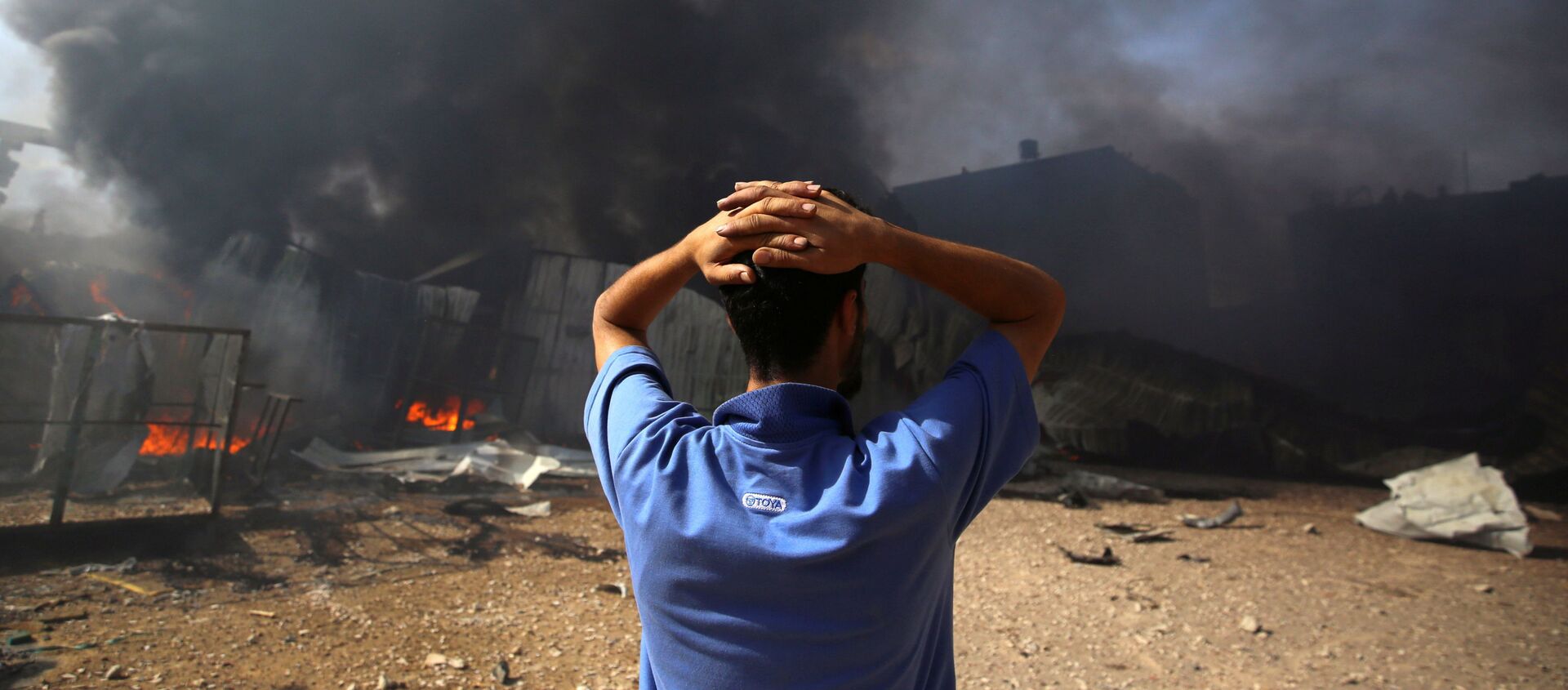 A man stands near a burning sponge factory after it was hit by Israeli artillery shells, according to witnesses, in the northern Gaza Strip May 17, 2021 - Sputnik International, 1920