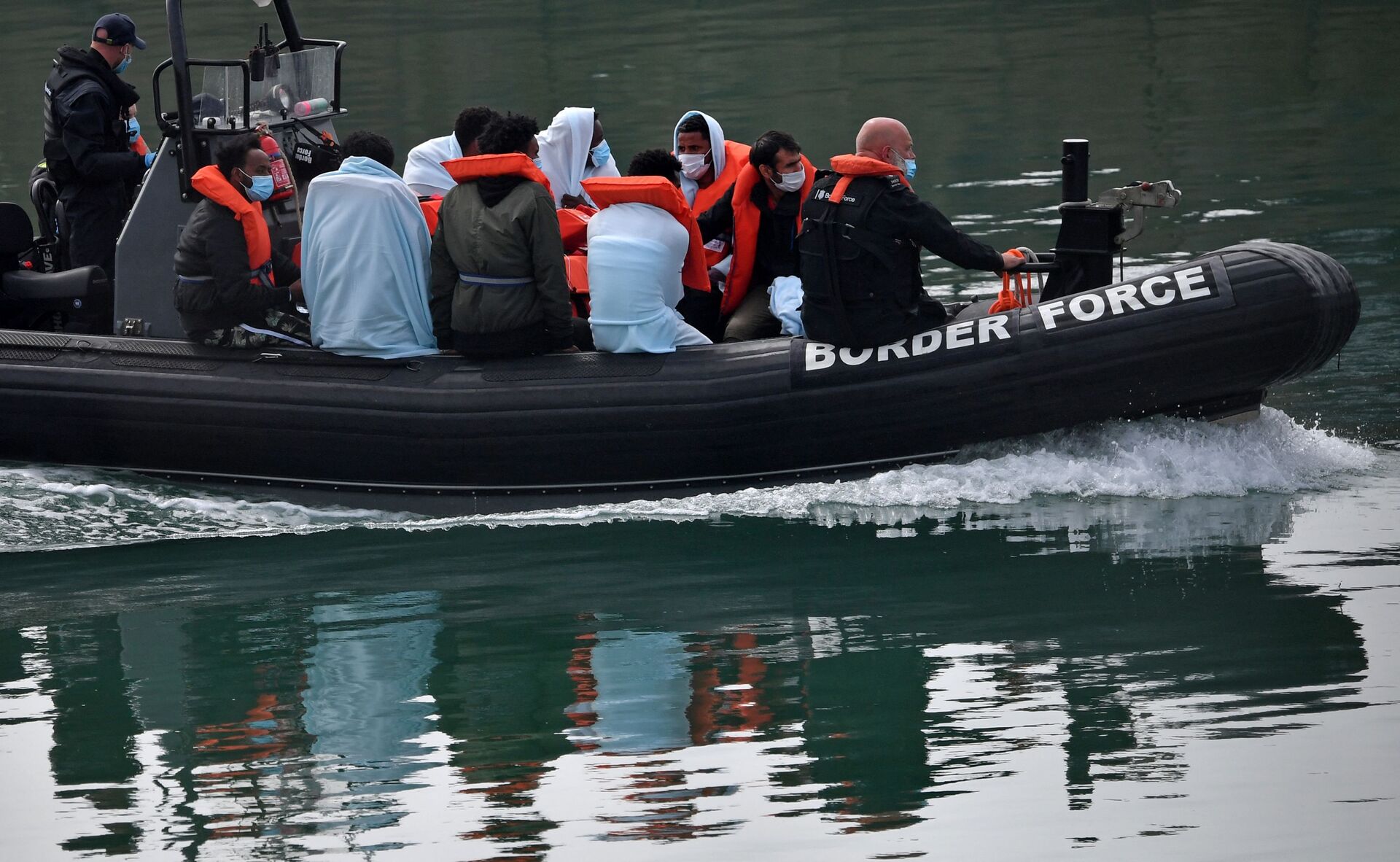 UK Border Force officials travel in a RIB with migrants picked up at sea whilst Crossing the English Channel, as they arrive at the Marina in Dover, southeast England on August 15, 2020 - Sputnik International, 1920, 09.09.2021