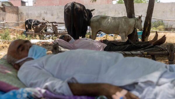 Villagers with breathing difficulties rest in cots as they receive treatment at a makeshift open-air clinic, amidst the spread of the coronavirus disease (COVID-19), in Mewla Gopalgarh village in Jewar district in the northern state of Uttar Pradesh, India, 16 May 2021 - Sputnik International