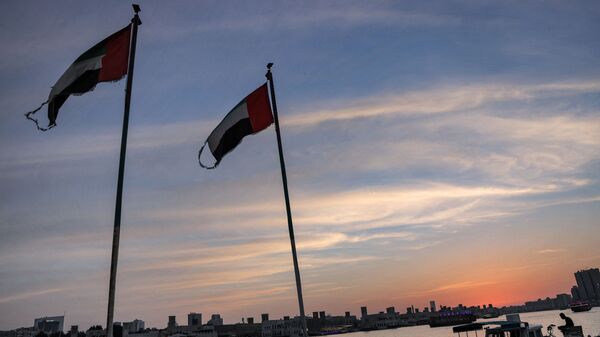 This picture taken on May 2, 2021 shows Emirati flags flying by boats moored along the Dubai creek at sunset. (Photo by GIUSEPPE CACACE / AFP) - Sputnik International