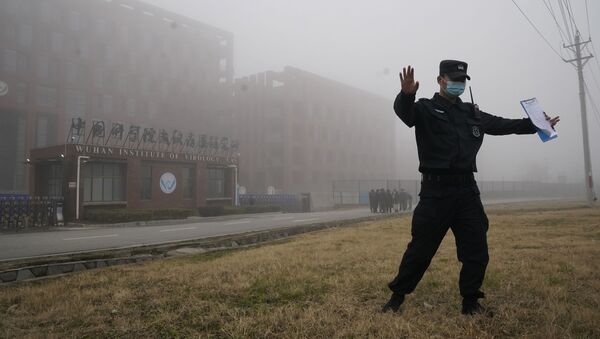 A security official moves journalists away from the Wuhan Institute of Virology after a World Health Organization team arrived for a field visit in Wuhan in China's Hubei province on Wednesday, Feb. 3, 2021 - Sputnik International