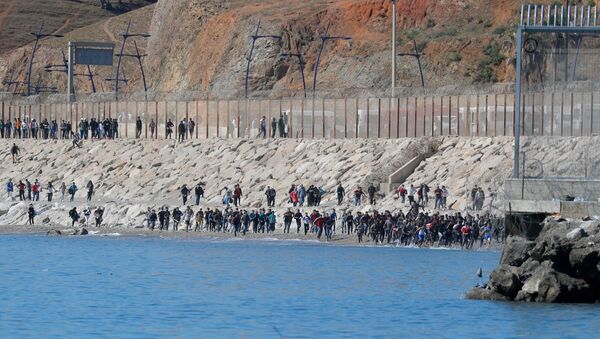 Migrants run towards the fence separating Morocco from Spain, after thousands of migrants swam across the border, in Ceuta, Spain, May 19, 2021. REUTERS/Jon Nazca - Sputnik International
