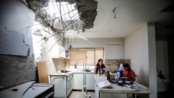 Family members of the Vaizel family, sit in the kitchen of their house which was damaged after it was hit by a rocket launched from the Gaza Strip earlier this week, in Ashkelon, Israel May 20, 2021 - Sputnik International