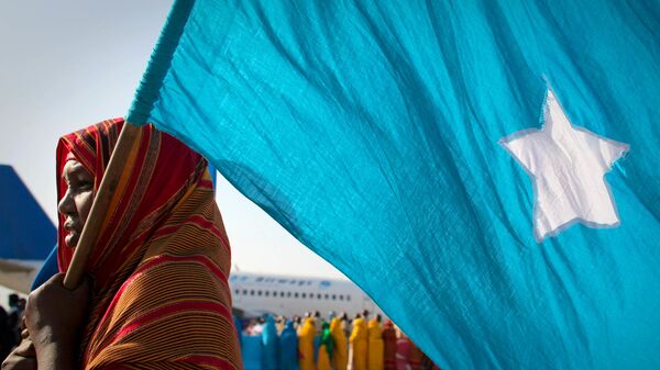 A woman holds the Somali flag at Mogadishu International Airport during a ceremony held 25 March to recieve the casket containing the body of fomer Somali president Abdullahi Yusuf Ahmed who died aged 77 at a hospital in the Gulf State of Abu Dhabi 23 March. Following the ceremony, Yusef's body was flown to his birthplace in Puntland where he was laid to rest - Sputnik International