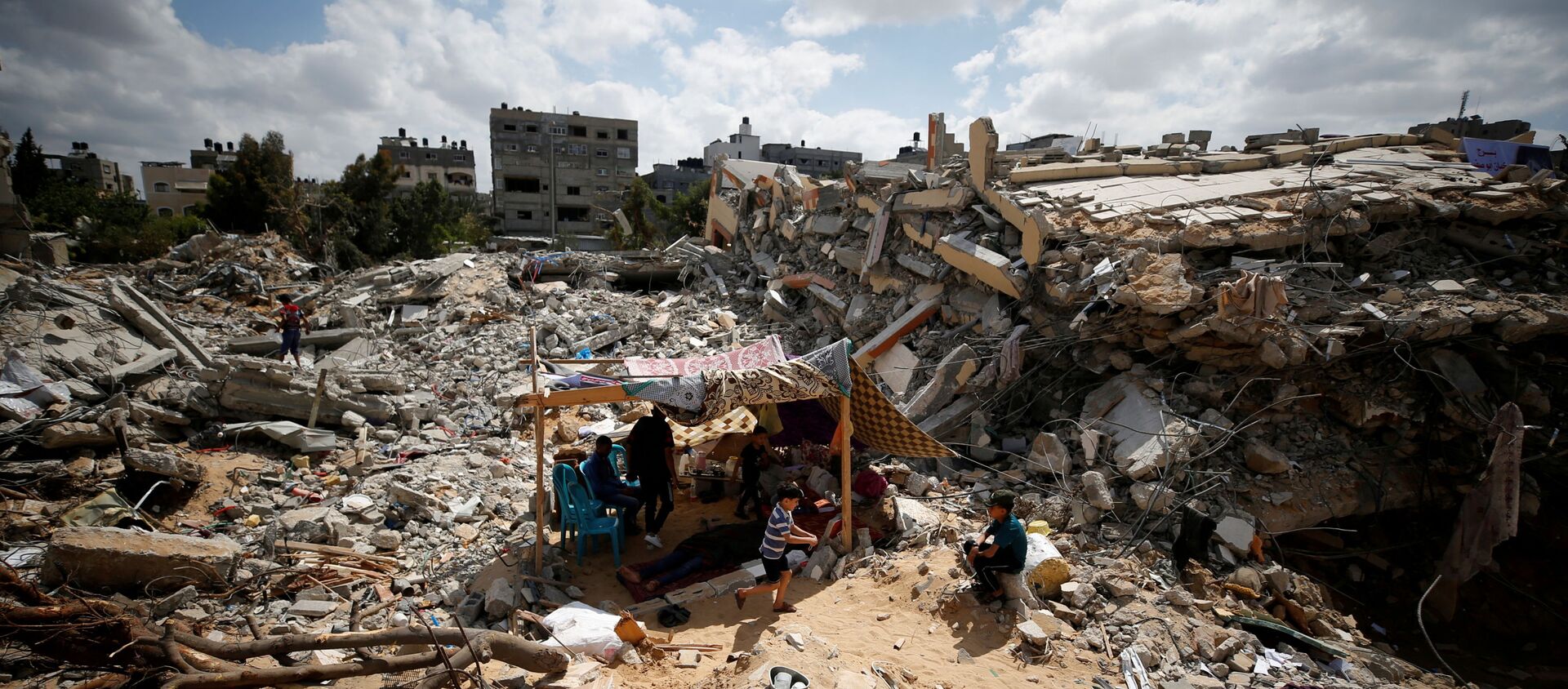 Palestinians sit in a makeshift tent amid the rubble of their houses, which were destroyed by Israeli air strikes during the Israel-Hamas fighting in Gaza, 23 May 2021. REUTERS/Mohammed Salem  TPX IMAGES OF THE DAY - Sputnik International, 1920, 24.05.2021