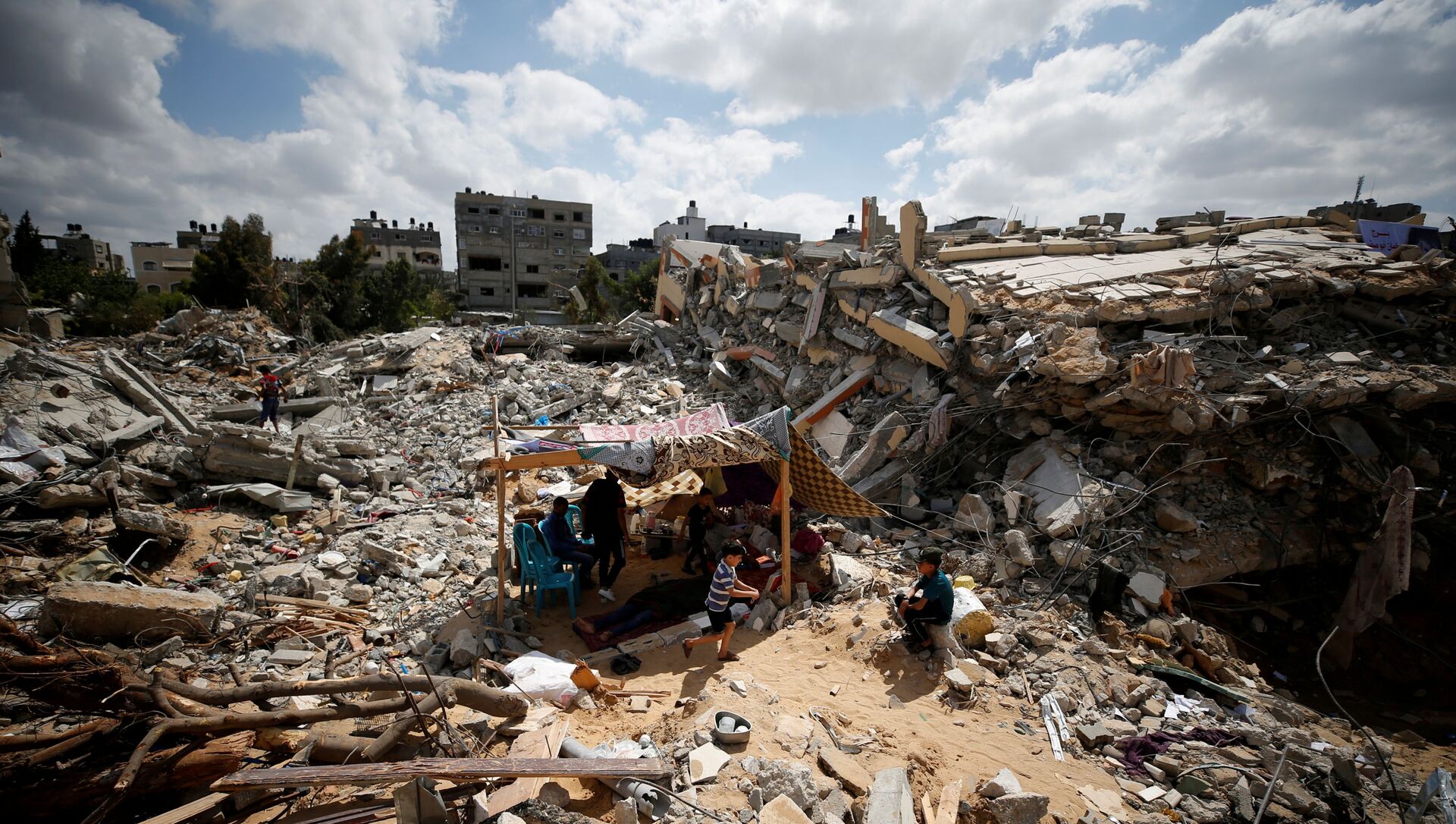 Palestinians sit in a makeshift tent amid the rubble of their houses which were destroyed by Israeli air strikes during the Israel-Hamas fighting in Gaza May 23, 2021. REUTERS/Mohammed Salem     TPX IMAGES OF THE DAY - Sputnik International, 1920, 23.05.2021