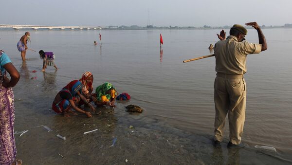 An Indian policeman, right, alongside Hindu women perform rituals by the Sarayu River in Ayodhya, about, 550 kilometers (350 miles) east of New Delhi, India, Sunday, Aug. 25, 2013 - Sputnik International