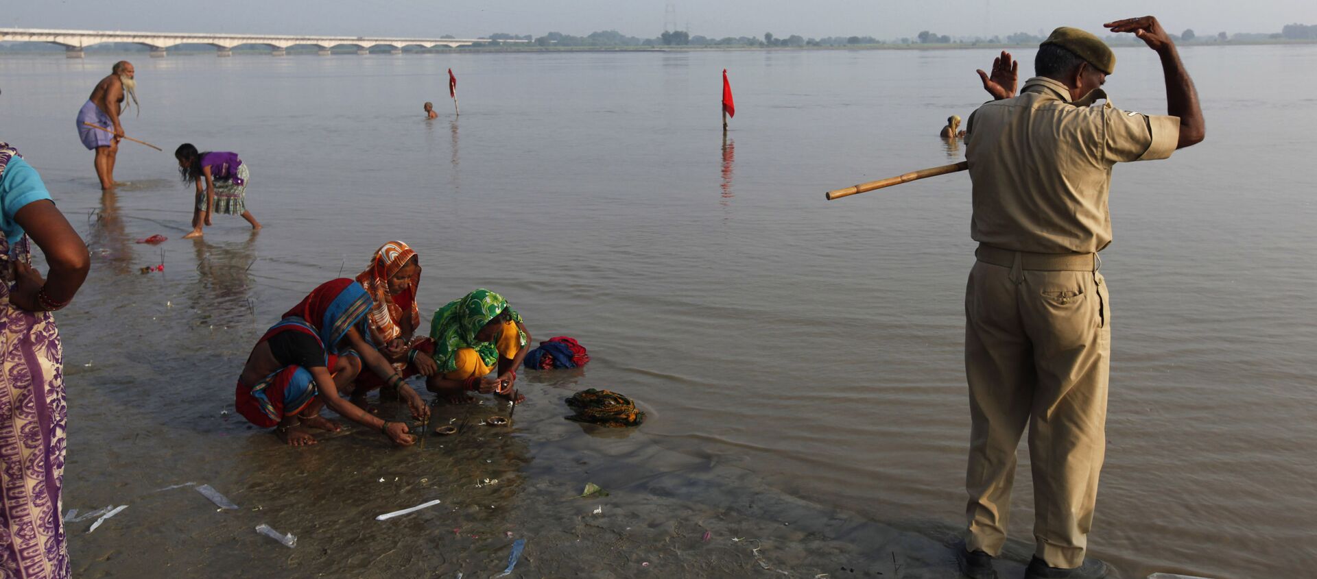 An Indian policeman, right, alongside Hindu women perform rituals by the Sarayu River in Ayodhya, about, 550 kilometers (350 miles) east of New Delhi, India, Sunday, Aug. 25, 2013 - Sputnik International, 1920, 24.05.2021