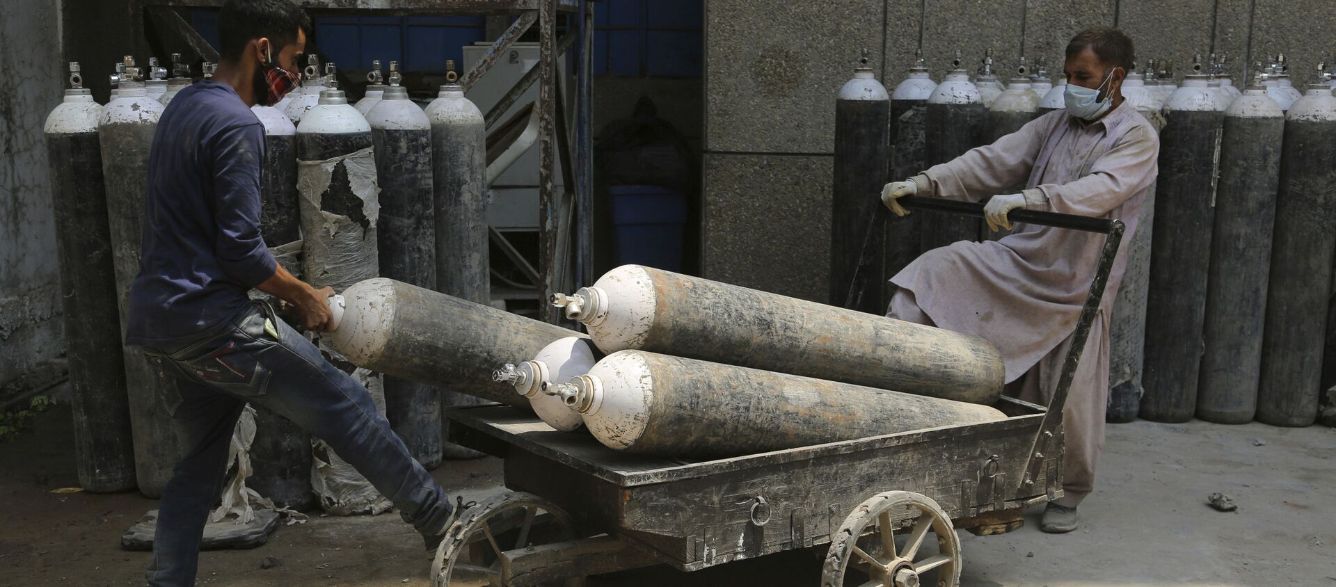 Workers load oxygen cylinders onto a hand cart to be carried inside the COVID-19 wards at a government run hospital in Jammu, India, Friday, May 7, 2021 - Sputnik International, 1920, 24.05.2021