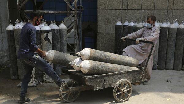 Workers load oxygen cylinders onto a hand cart to be carried inside the COVID-19 wards at a government-run hospital in Jammu, India, Friday, 7 May 2021 - Sputnik International