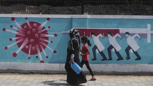 A woman along with a girl walk past a graffiti, depicting the coronavirus in Mumbai, India, Tuesday, April 6, 2021 - Sputnik International