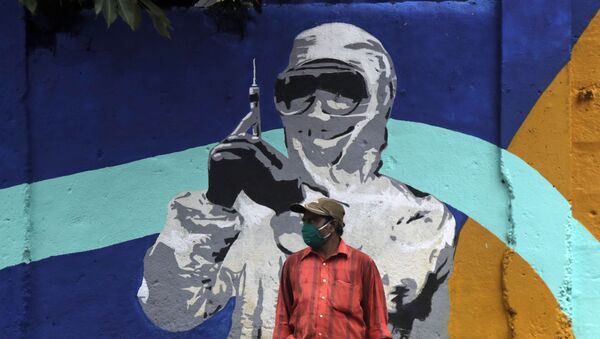 A man stands in front of a graffiti honoring those in the frontlines in the fight against the coronavirus in Mumbai, India, Tuesday, July 7, 2020 - Sputnik International