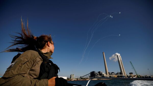 An Israeli soldier looks on as Israel's Iron Dome anti-missile system intercept rockets launched from the Gaza Strip towards Israel, as it seen from a naval boat patrolling the Mediterranean Sea off the southern Israeli coast as Israel-Gaza fighting rages on May 19, 2021 - Sputnik International